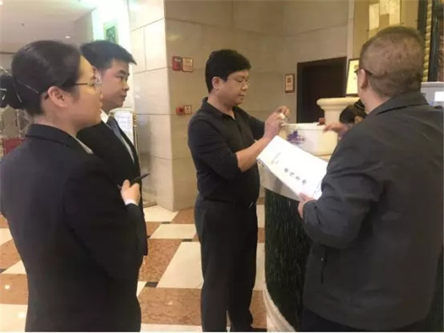 圖為陳剛局長對照創(chuàng)建標(biāo)準(zhǔn)檢查銀天酒店便民醫(yī)藥箱