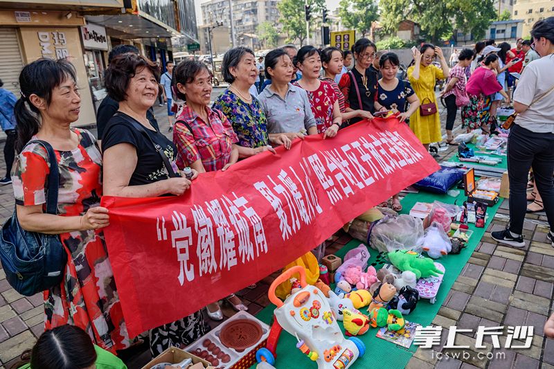社區(qū)參加愛(ài)心義賣的大媽們打出了自己的義賣橫幅,。