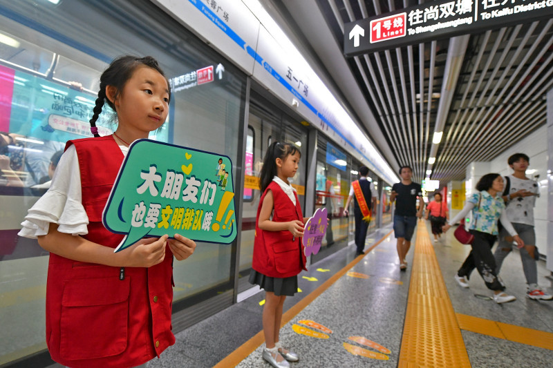 長沙地鐵五一廣場站內(nèi)，身穿紅色志愿者馬甲的萌娃在地鐵工作人員的帶領(lǐng)下一同維護(hù)車站文明秩序,，引來乘客紛紛點(diǎn)贊,。 長沙晚報(bào)全媒體記者 王志偉 攝