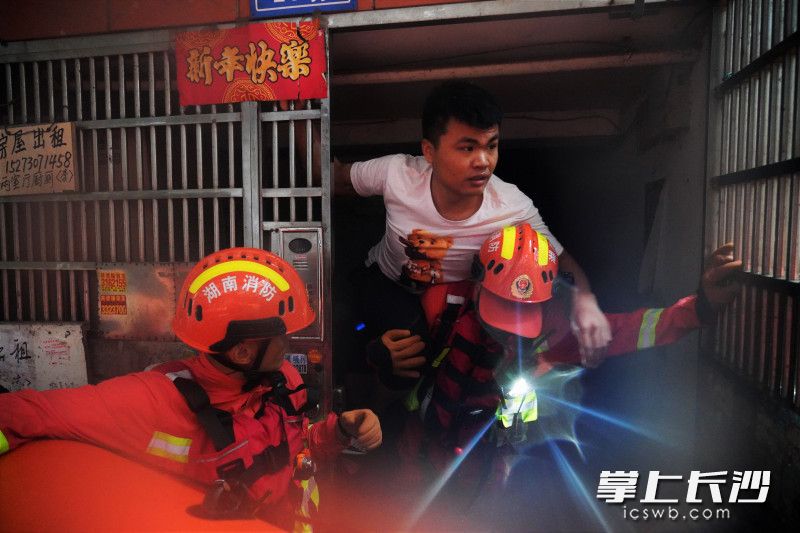 在岳陽(yáng)樓區(qū),，消防員將樓道中的被困群眾背上皮劃艇,。長(zhǎng)沙晚報(bào)通訊員 黎翔 攝