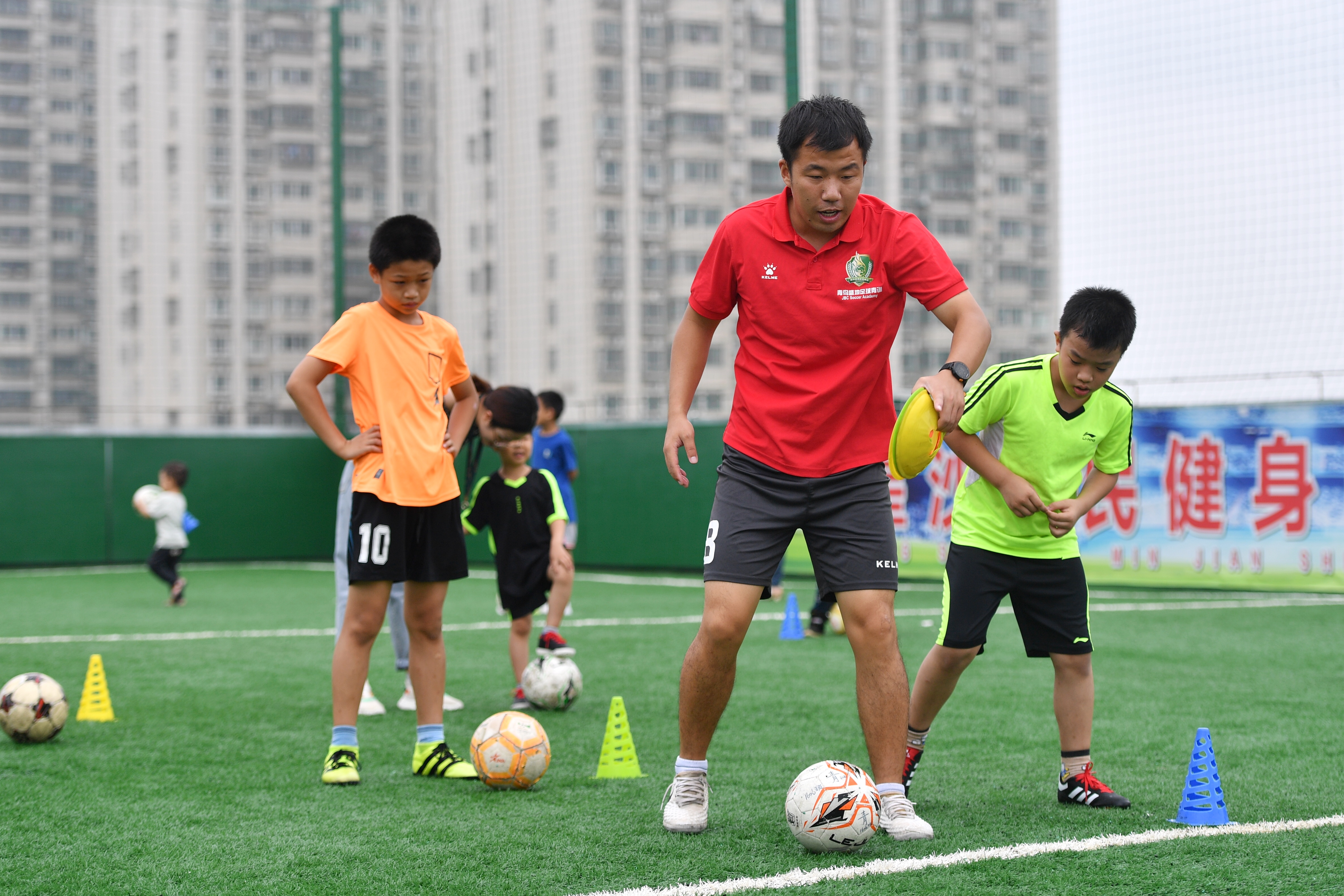 7月20日,，星沙全民健身中心內(nèi),，孩子們在教練的指導(dǎo)下進行足球練習(xí)。