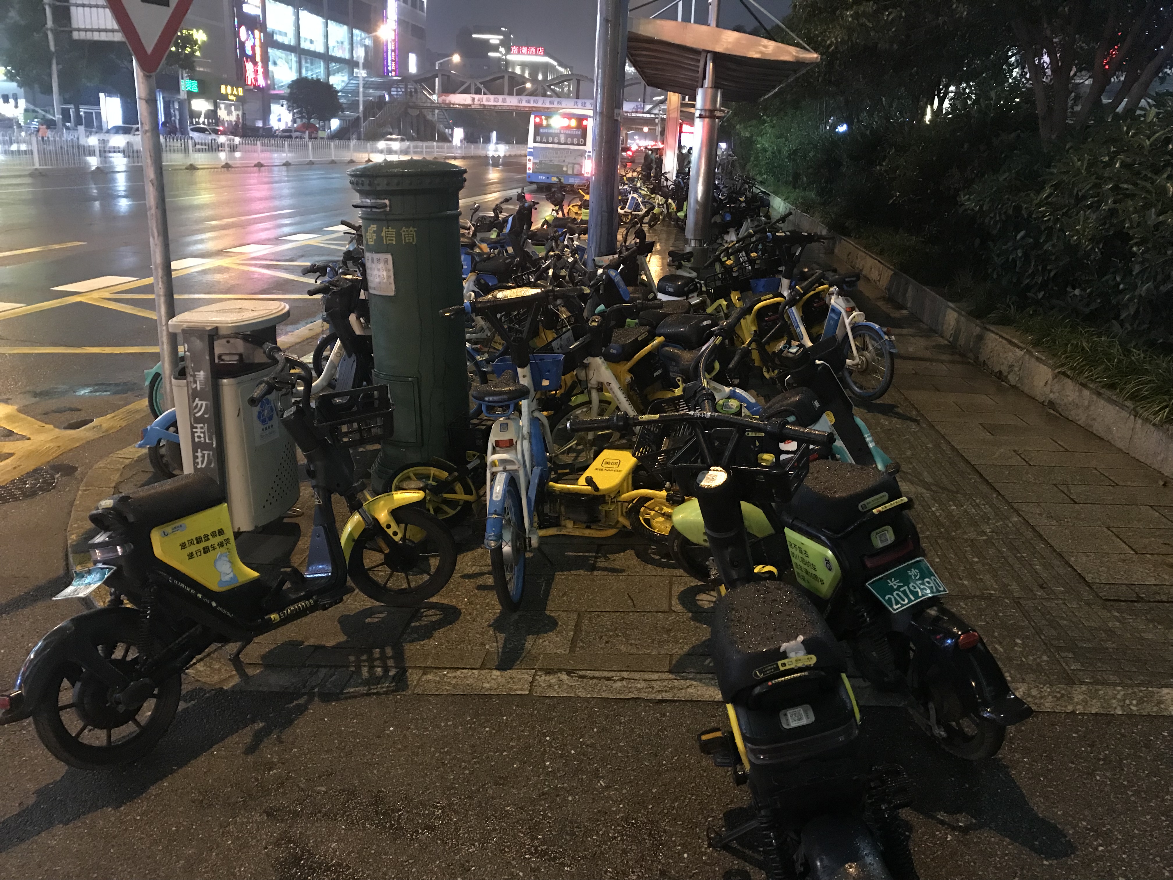 有牌和無牌共享電單車把公交車站圍成了一個孤島。 均為長沙晚報全媒體記者吳鑫礬攝