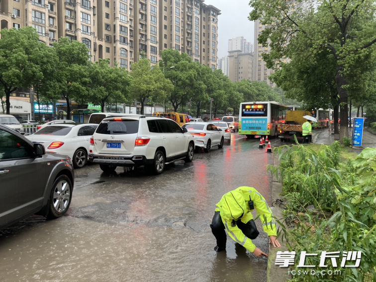 歐陽誠帶領(lǐng)中隊警力在現(xiàn)場一邊疏導(dǎo)交通,，一邊彎下腰用手清理下水口淤積物,，徒手疏通被堵住的排水口。