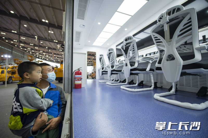 在鐵建重工展臺，一位家長帶著孩子看著仿佛科幻片中的車載主控室,。