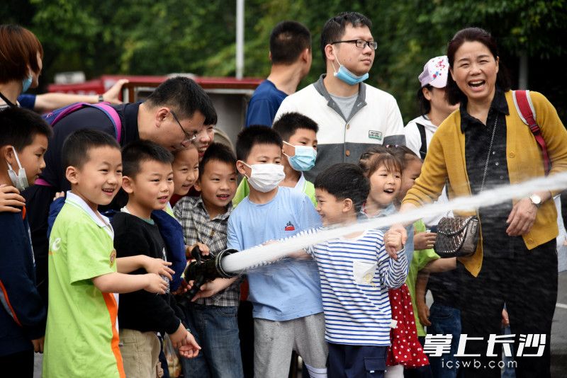 孩子們在家長的陪同下，體驗消防水槍出水“滅火”,。