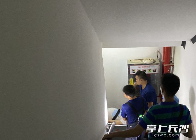 消防員小心翼翼,，抬著擔架一層一層走樓梯下樓,。