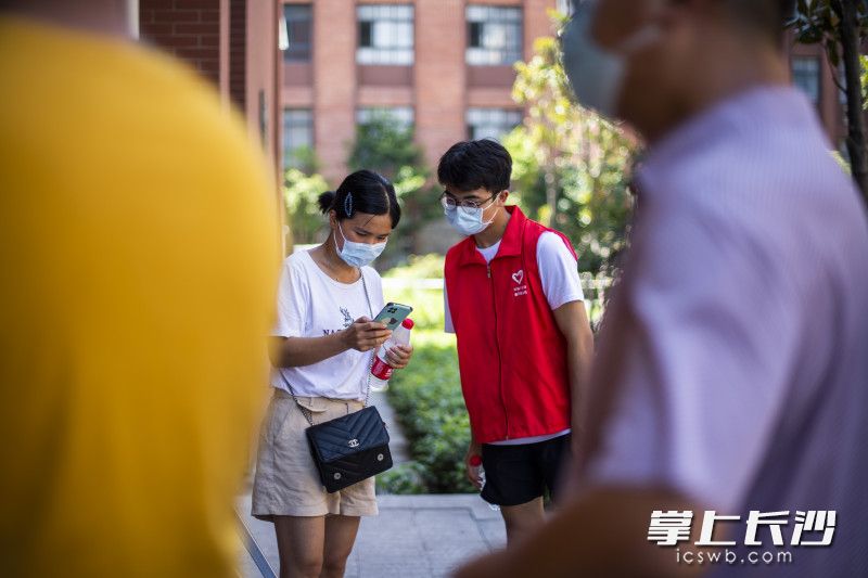 上午10點(diǎn),，在開福區(qū)一中核酸檢測點(diǎn)，18歲的準(zhǔn)大學(xué)生李紅生在指導(dǎo)市民用手機(jī)進(jìn)行核酸登記,。