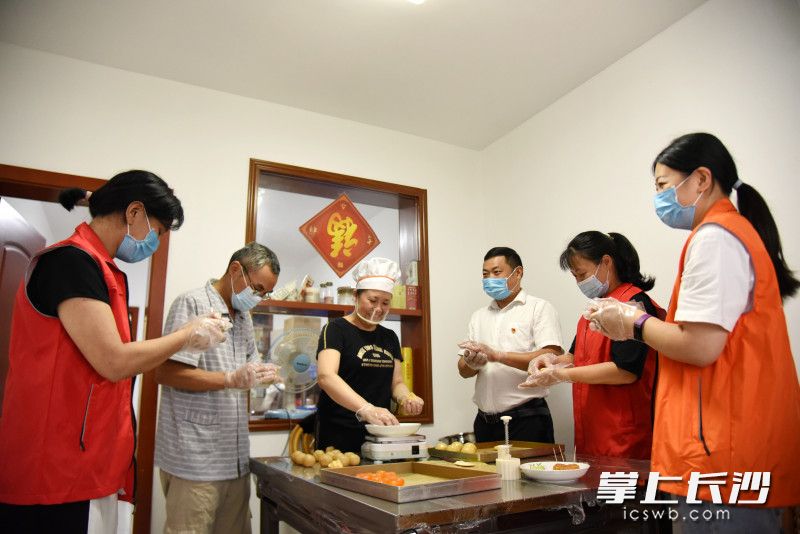 9月15日，“長沙好人”葉宗武,、段輝群（左三）夫妻和孫家闖（右三）在“段媽媽烘焙坊”與志愿者一道,，為社區(qū)困難群眾做月餅。  均為長沙晚報全媒體記者劉琦攝