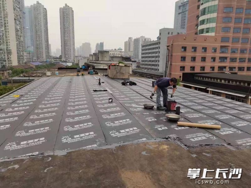 工作人員正在對漏水屋頂進行翻修,。