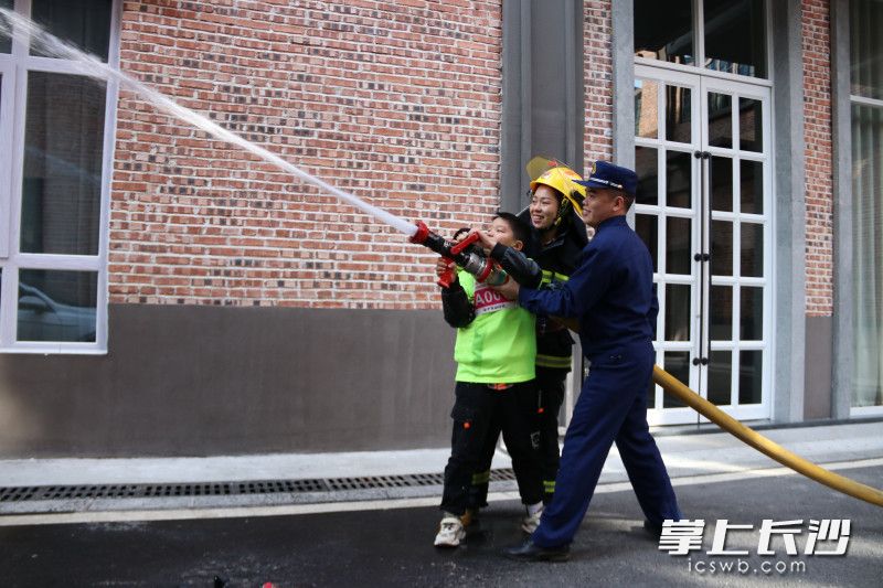 活動現(xiàn)場，追風少年,、家長共同體驗消防員的滅火救援“日?！薄＞鶠殚L沙晚報通訊員 馮運文 供圖