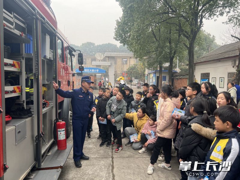 消防宣傳人員為同學(xué)們介紹消防車上的裝備。