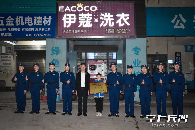 在秦勇忠的洗衣店前,，東方紅消防救援站消防員特意來(lái)與他分享喜悅,，合影留念。長(zhǎng)沙晚報(bào)通訊員 李文翠 供圖