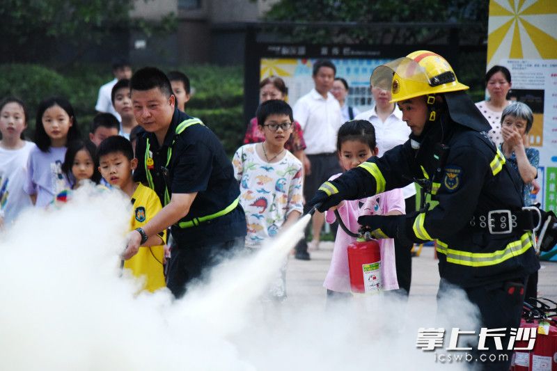 在“火焰藍”和物業(yè)人員的帶領(lǐng)下,，中小學(xué)生上前體驗用干粉滅火器滅火。