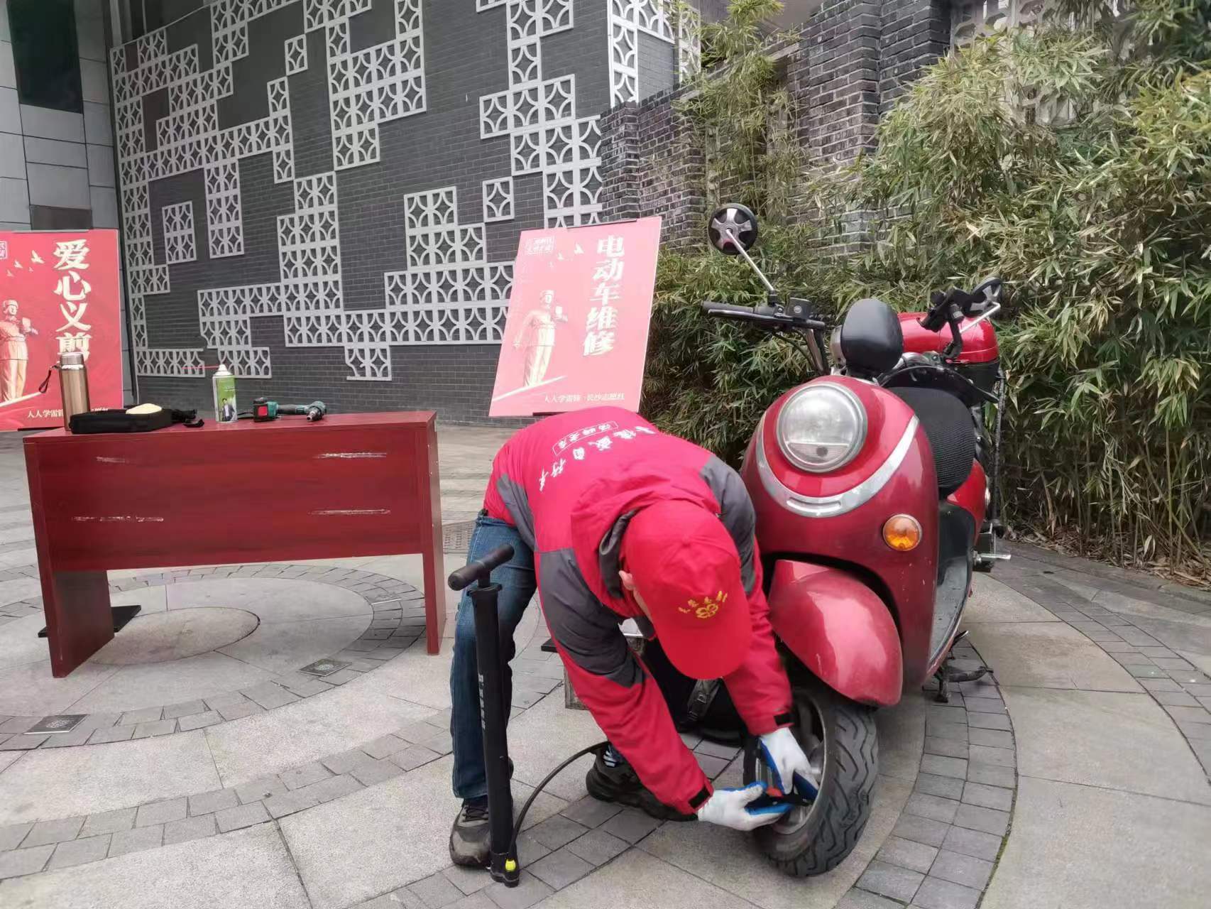 志愿者正在認(rèn)真為居民修理電動(dòng)車(chē),。