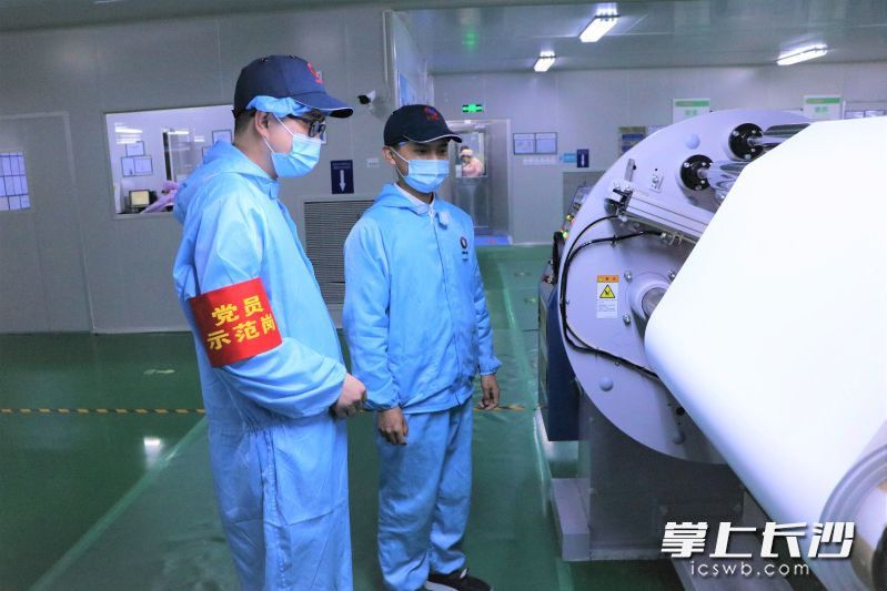 在中材鋰膜涂覆工廠里，負(fù)責(zé)人王連杰（左）正在查看涂覆膜收卷情況,。長沙晚報全媒體記者 張禹 通訊員 趙璞 攝