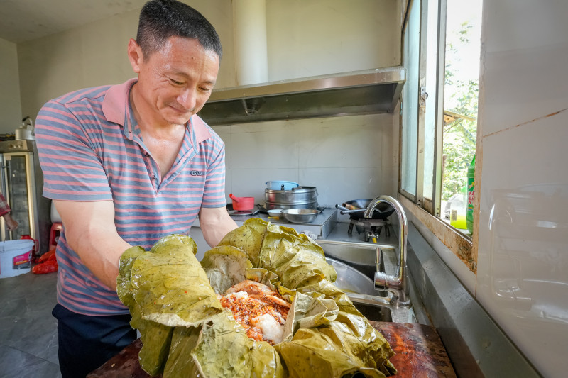 在寧鄉(xiāng)資福紅旗村的荷葉燒雞老店，袁定明是第四代美食傳承人,，他用五層清香四溢的荷葉包裹腌制好的土雞,。