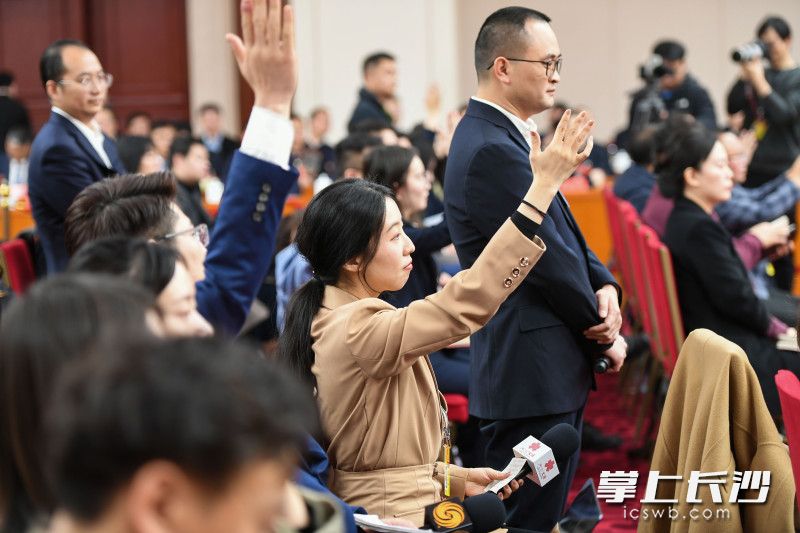 記者們在舉手提問,。