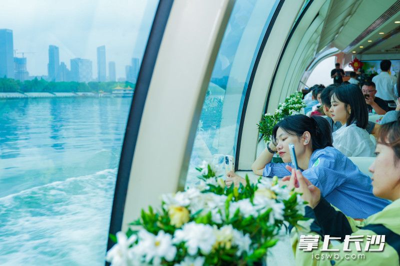 “梔香長沙”號游輪正式起航，游船上花香四溢,，游客們正在打卡拍照,。