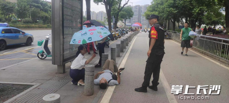 長沙市中心醫(yī)院工作人員談慧打著傘照顧著倒地老人，等待急救人員的到來,。醫(yī)院供圖