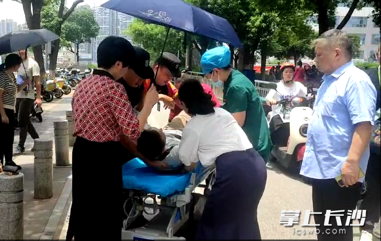 長沙市民和長沙市中心醫(yī)院工作人員共同攜手將倒地老人抬上擔架,。醫(yī)院供圖