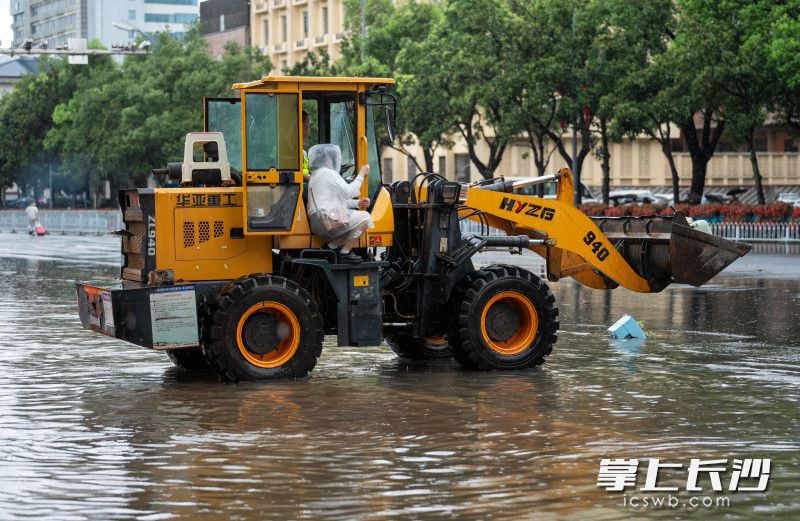 五一大道曉園路口一輛鏟車帶著去火車站趕車的乘客渡過積水區(qū),。