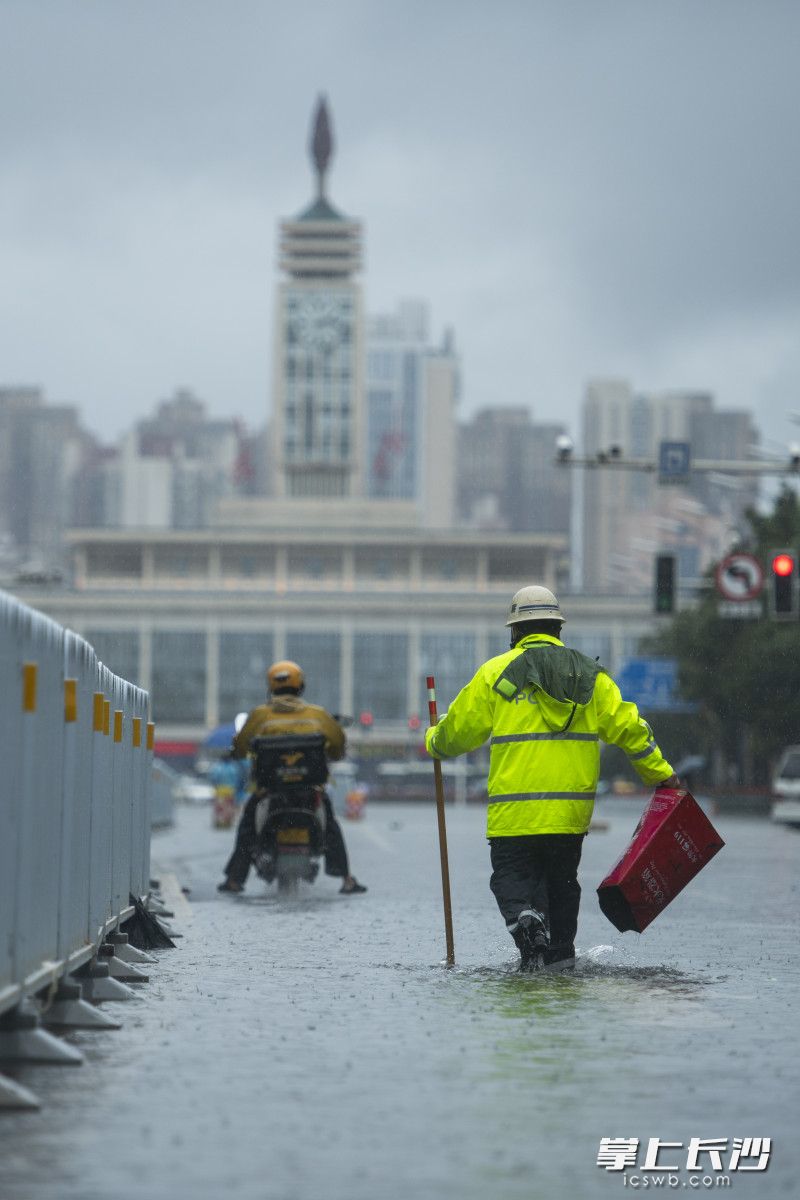 6月24日14時11分，五一大道一處積水路段水位快速下降,，一位芙蓉交警拿著木棍試探水深,，以考慮車輛可否通行，還不時撿起路面雜物,。