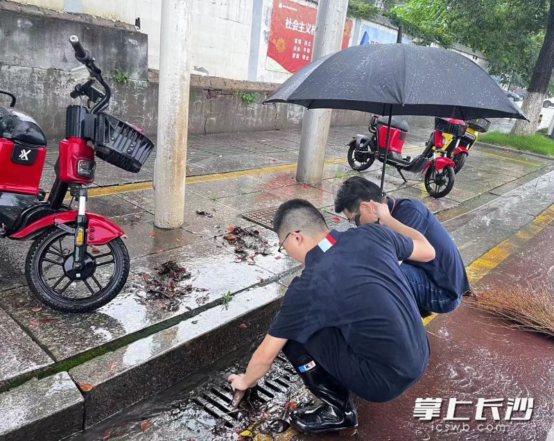 社區(qū)工作者清理堵塞的下水道,。