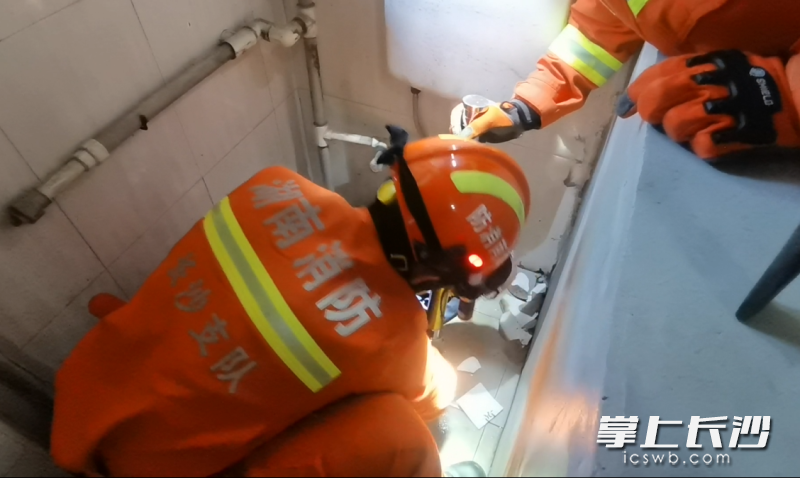 消防救援人員小心翼翼地使用錘子和手動破拆工具組對廁所進行破拆,。長沙晚報通訊員 尋艷 供圖