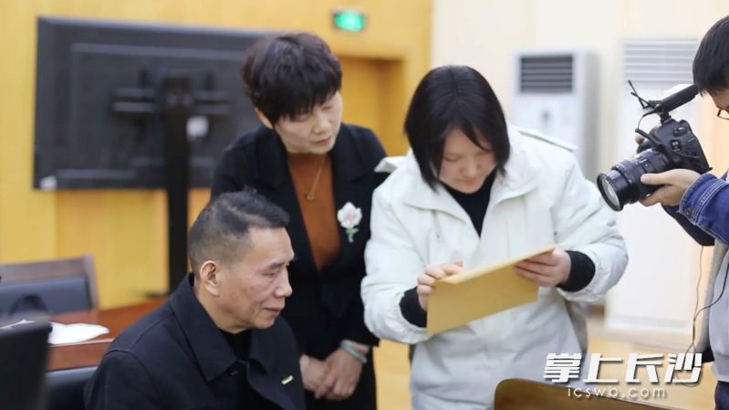 盲文老師給劉先生（左一）念判決書(shū)的內(nèi)容。 長(zhǎng)沙晚報(bào)全媒體記者 李廣軍 攝