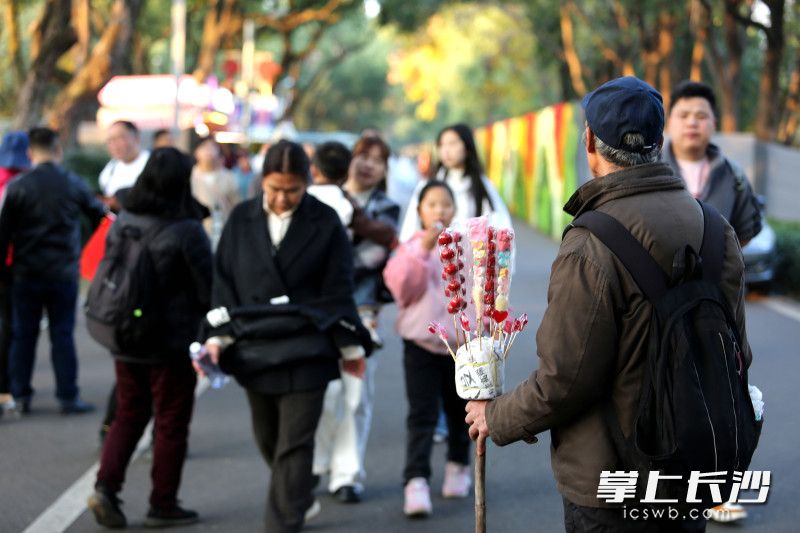 一小販在站在步道中央叫賣冰糖葫蘆,。 均為長沙晚報全媒體記者賀文兵攝