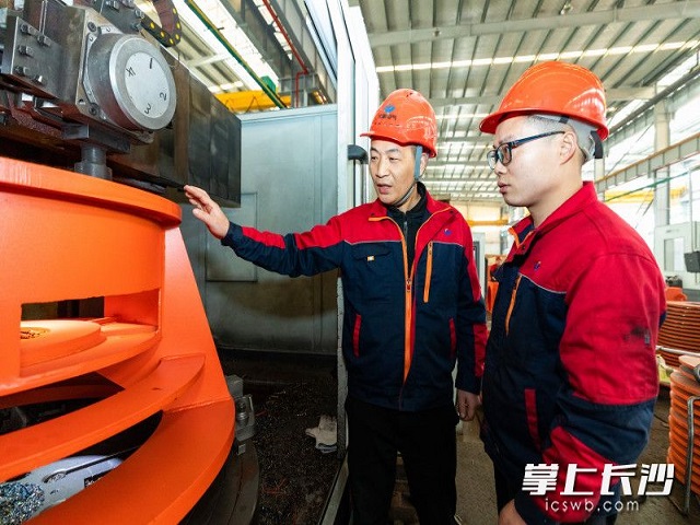 長利電氣生產(chǎn)車間里,，毛強（左）給技術(shù)工人介紹裝配注意事項。 均為長沙晚報全媒體記者董陽攝