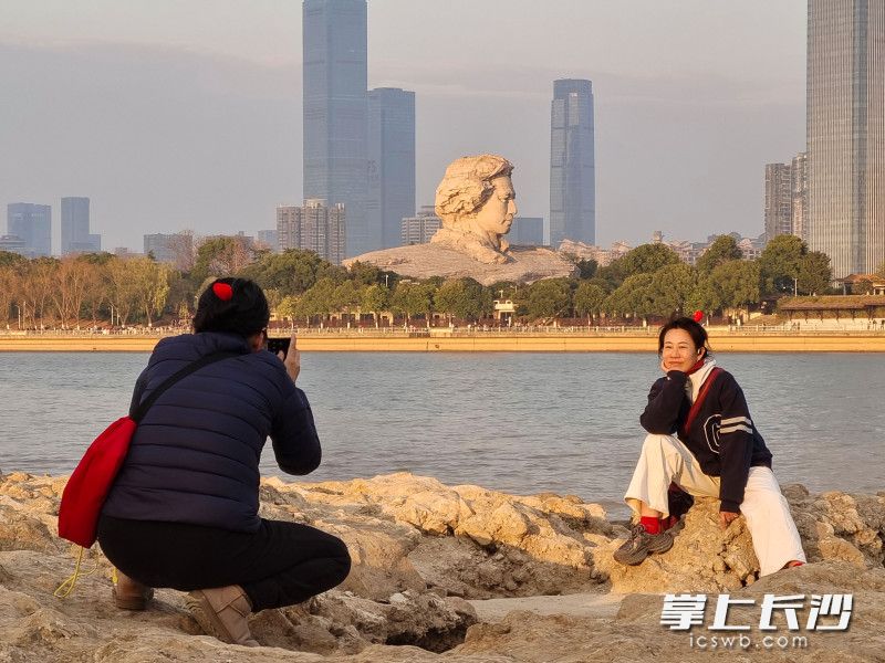游人在江灘公園與青年毛澤東藝術(shù)雕塑合影。
