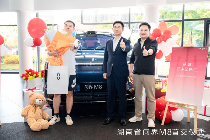 賽力斯汽車總裁何利揚（中）為問界M8車主送上鮮花和禮品。 均為鴻蒙智行供圖