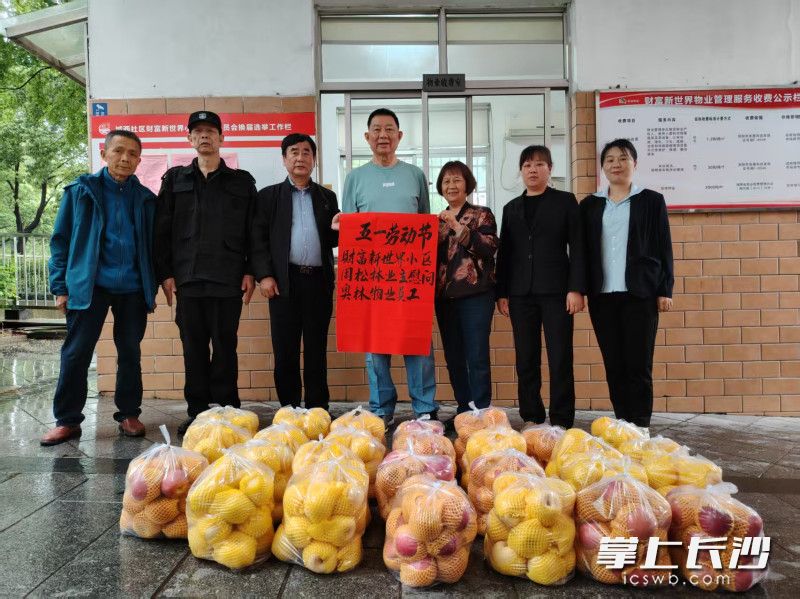 “五一”前夕,，周松林（左四）,、潘樂玲（左五）夫婦給物業(yè)公司全部28名工作人員送去了蘋果。  均為長沙晚報通訊員劉淮攝