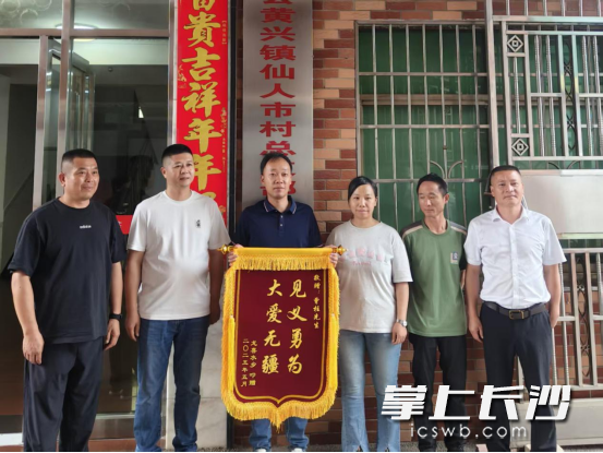 獲救家庭將印有“見(jiàn)義勇為 大愛(ài)無(wú)疆”的錦旗交到施救者手中。