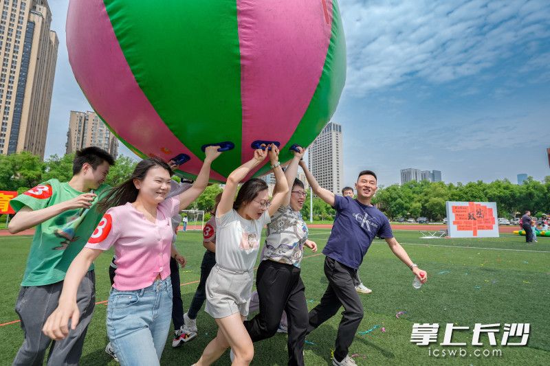 “鴻運(yùn)彩球”項(xiàng)目中,，8人團(tuán)隊(duì)合力托起巨型充氣球,，喊著整齊的“一二、一二”口號(hào)向前沖刺,。