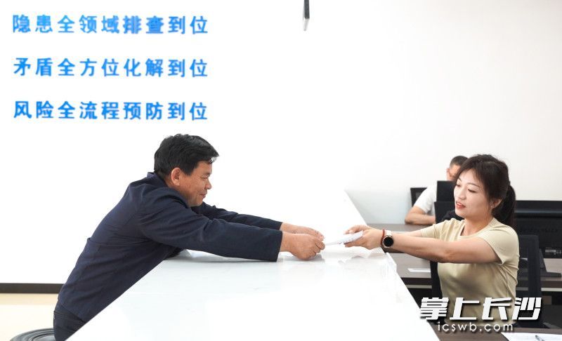 寧鄉(xiāng)市夏鐸鋪鎮(zhèn)綜治中心里,，村民向工作人員遞交申請材料。
