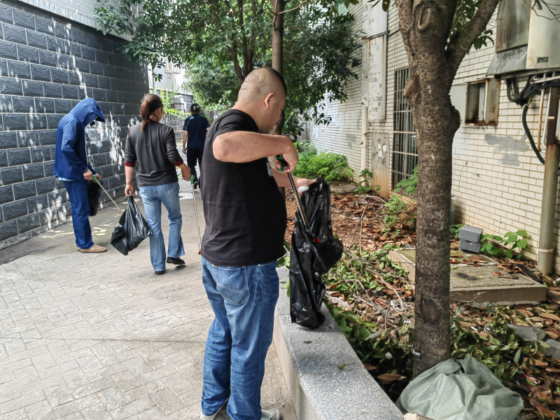 黨員們手持垃圾夾對綠化帶垃圾進行清理,。