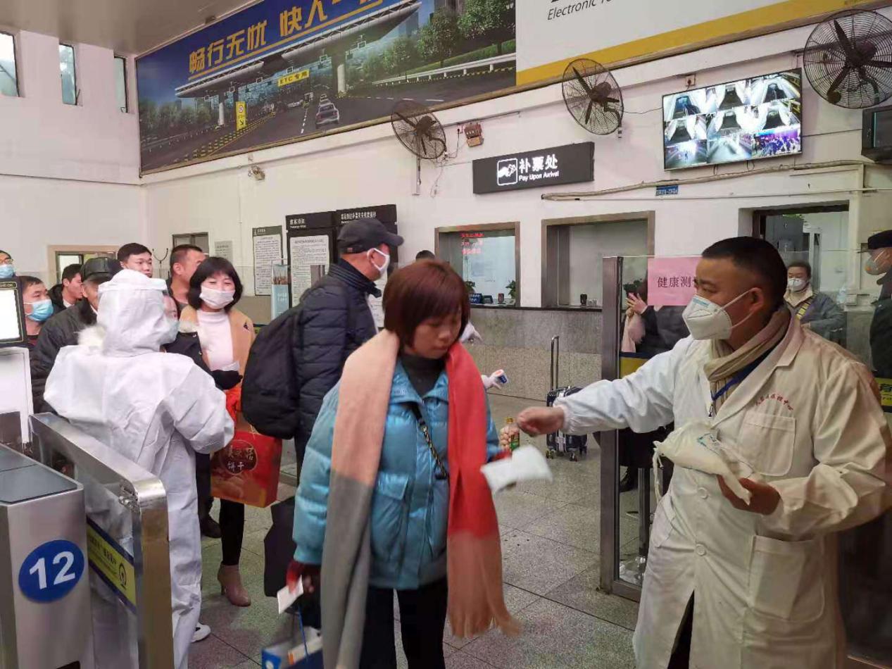 圖為陳怡軍在為火車站旅客發(fā)放口罩
