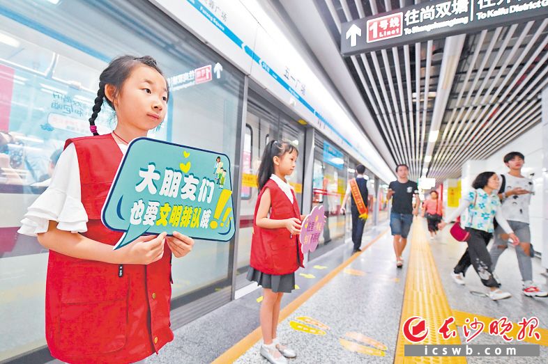 長沙地鐵五一廣場站內(nèi),，身穿紅馬甲的萌娃在地鐵工作人員的帶領(lǐng)下一同維護車站文明秩序。