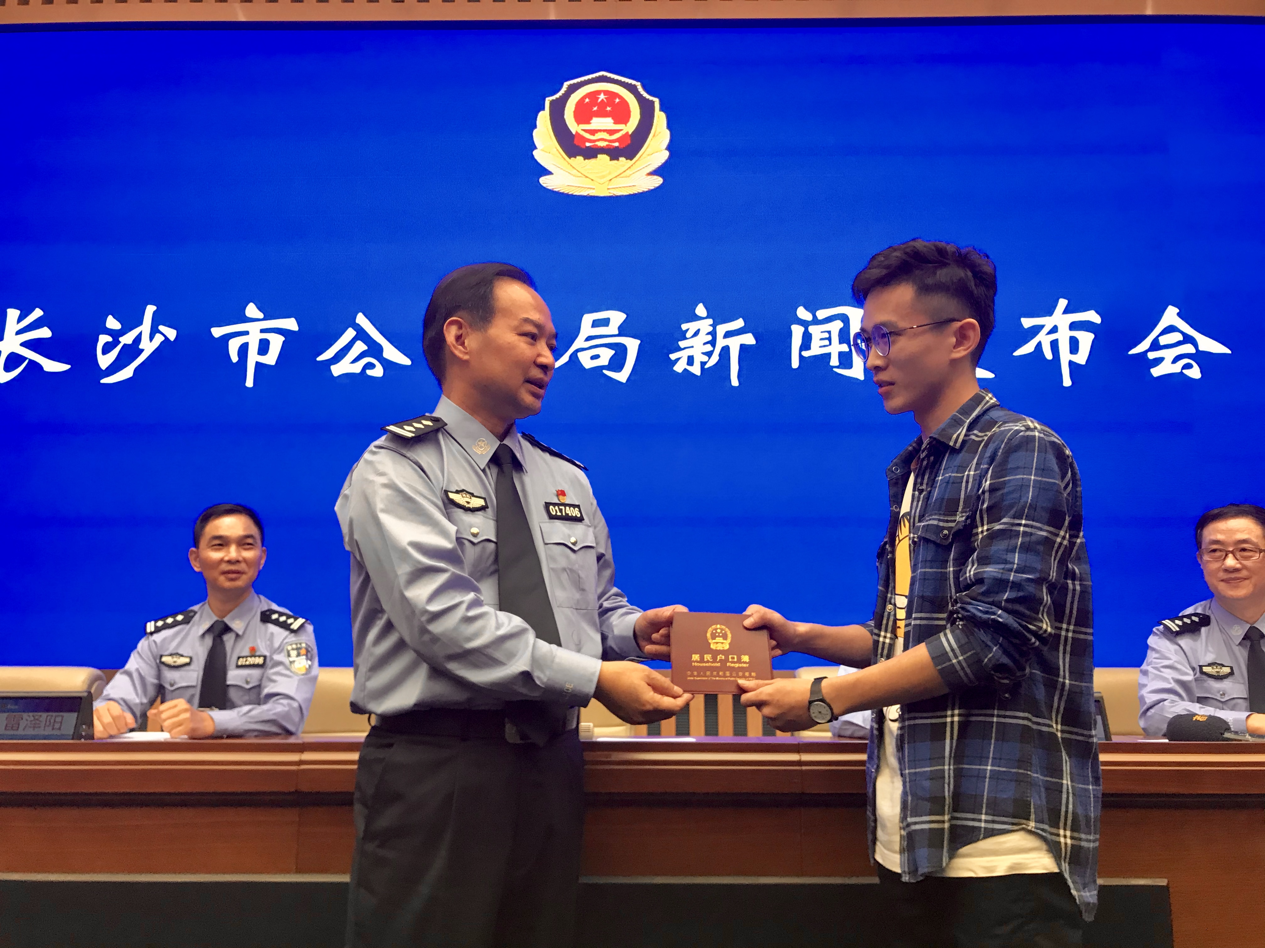 長沙市公安局人口與出入境管理支隊(duì)支隊(duì)長劉輝為居民楊程博發(fā)放戶口簿,，楊程博是長沙第一個(gè)在網(wǎng)上全流程辦理高校職院畢業(yè)生落戶的居民,。長沙晚報(bào)全媒體記者 聶映榮 攝