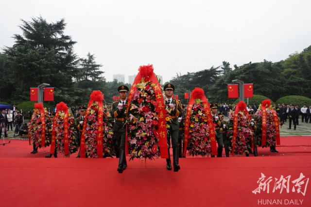 14名禮兵抬起花籃,，將花籃敬放在烈士紀念塔前。