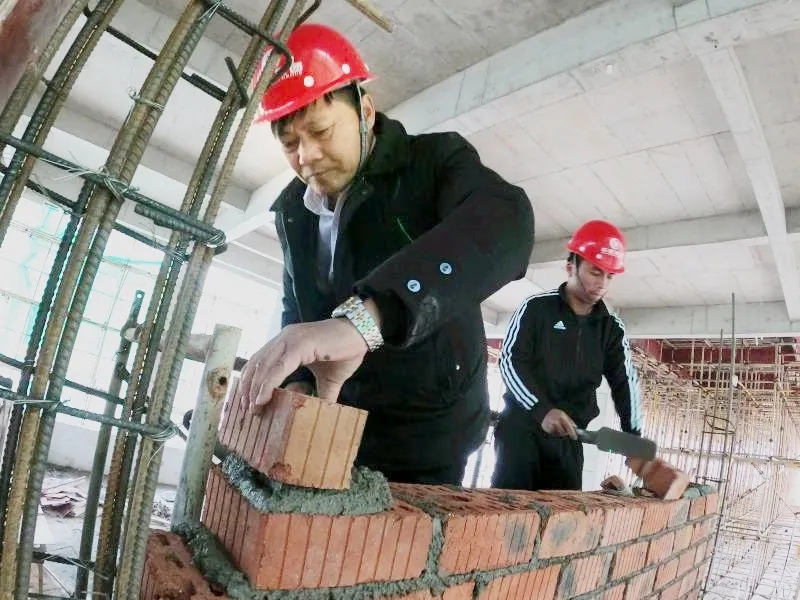 ▲周科明帶徒弟“傳幫帶”示范砌墻,。