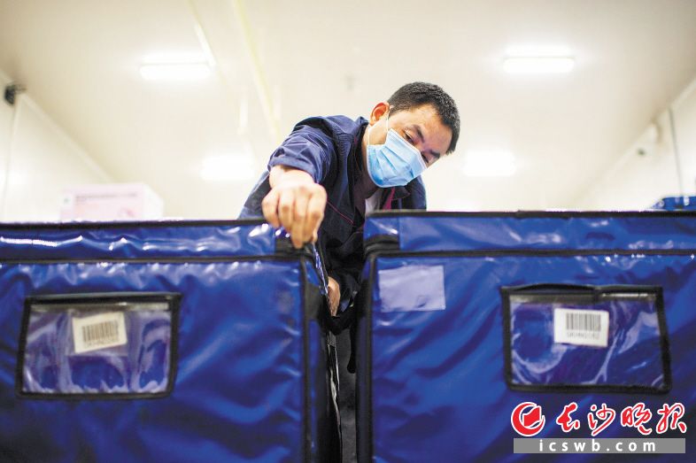 27日 19:21　　代運(yùn)冷鏈運(yùn)輸車司機(jī)郭國(guó)順將需要分發(fā)的疫苗裝進(jìn)冷鏈保溫箱。