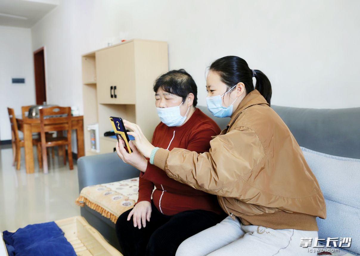 章桂芝（左）通過(guò)手機(jī)給街道辦事處工作人員介紹“兌獎(jiǎng)”的相關(guān)情況,。長(zhǎng)沙晚報(bào)全媒體記者 顏開(kāi)云 攝
