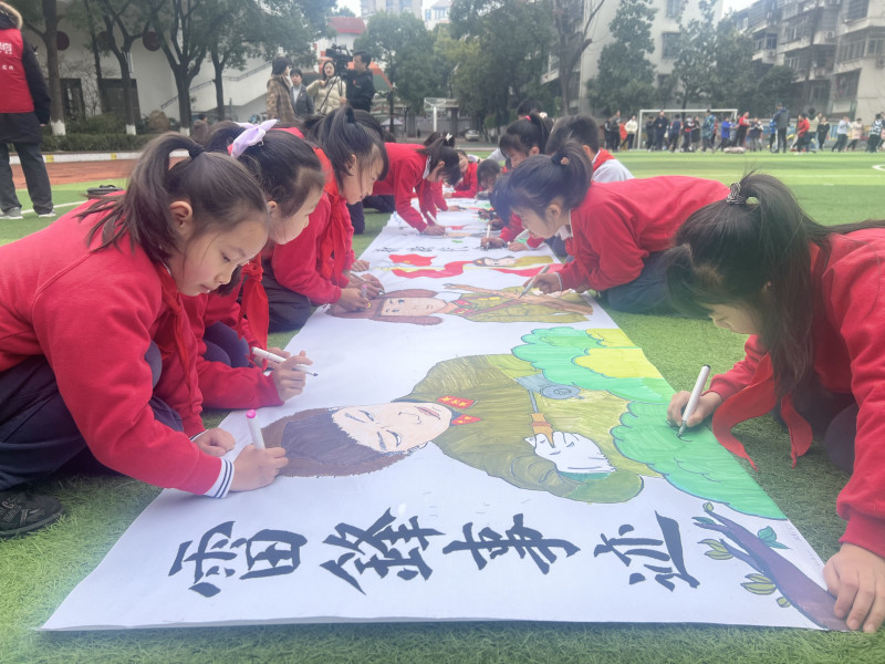 芙蓉區(qū)育才學(xué)校的操場上,，孩子們在10米長卷上繪下奉獻故事，感受雷鋒精神的傳承,。長沙晚報通訊員馮適攝