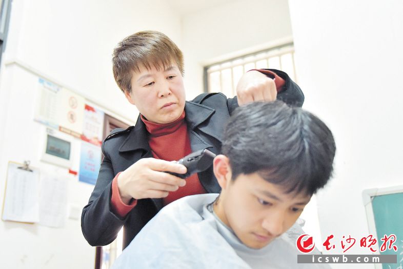 在值班室里，生活老師申玉娥為學(xué)生免費(fèi)剪頭發(fā),?！　￠L沙晚報(bào)全媒體記者 劉琦 通訊員 皮佳怡 攝影報(bào)道