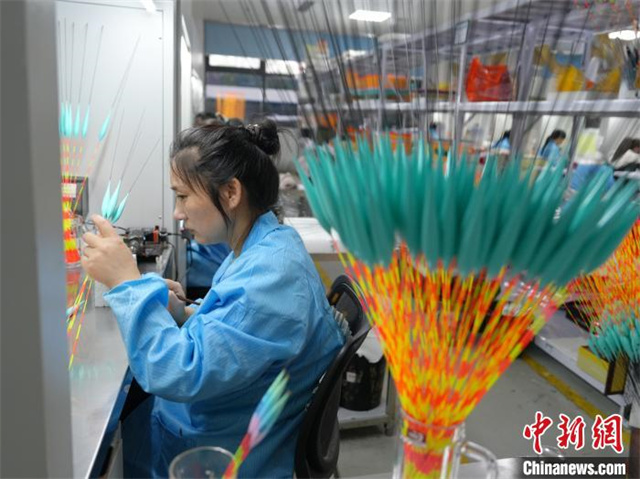 The photo shows a worker painting fishing floats. (Photo/Yang Huafeng, Chinanews)?
