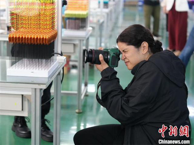 The photo shows a Brazilian photographer taking pictures of fishing floats. (Photo/Yang Huafeng, Chinanews)