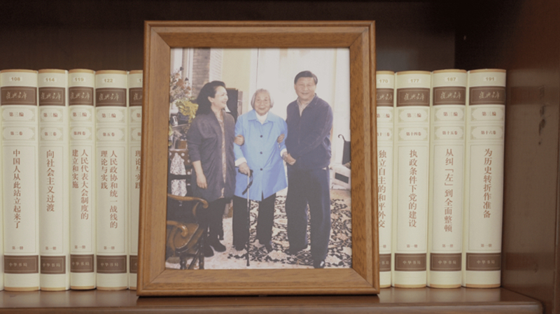 △ 習近平辦公室的書架上放著一張照片,，照片中他和愛人彭麗媛攙扶著母親。